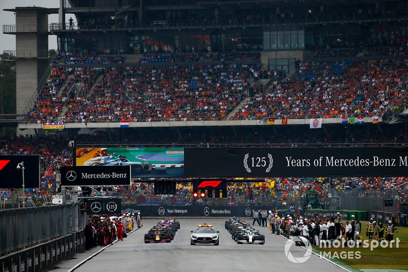 The Safety Car leads Lewis Hamilton, Mercedes AMG F1 W10, Max Verstappen, Red Bull Racing RB15, and the rest of the field away