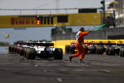 The lights come on and a marshal gives the green flag for the start