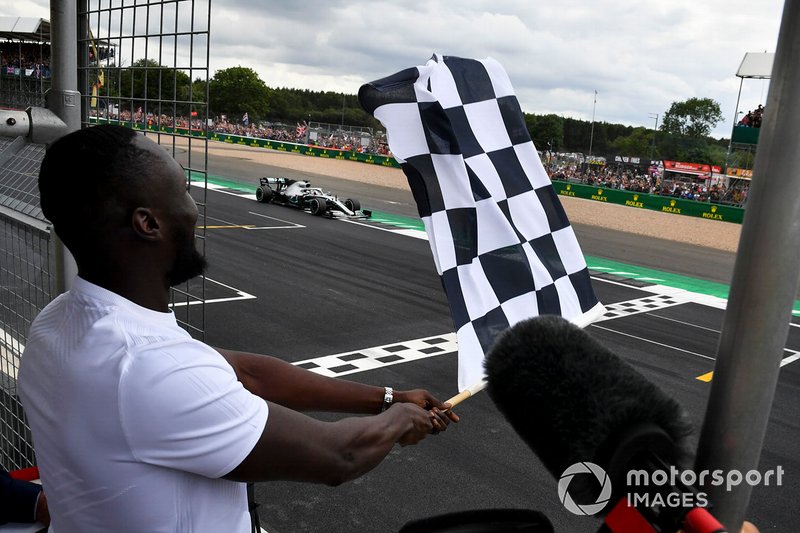 Rapper Stormzy zwaait de finishvlag terwijl Lewis Hamilton in zijn Mercedes AMG F1 W10 over de finishlijn komt