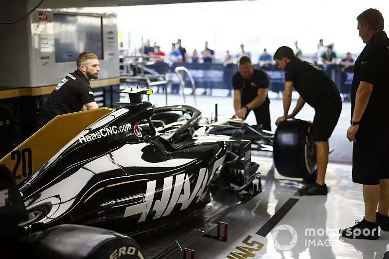 Mechanics work on the Kevin Magnussen Haas F1 Team VF-19 in the team's pit garage