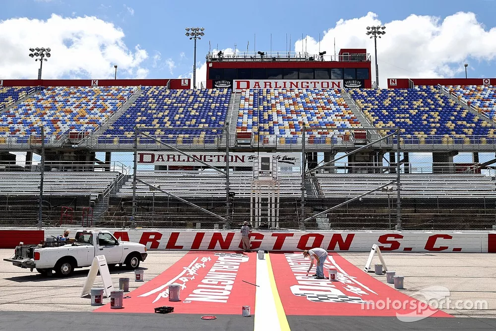 Track workers paint logos on the front stretch