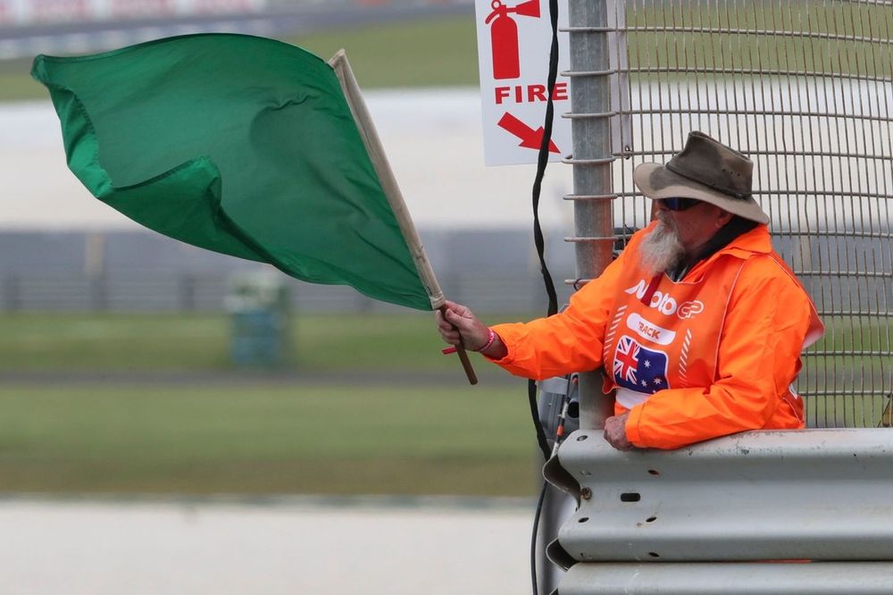 Oficial de pista ondeando la bandera verde