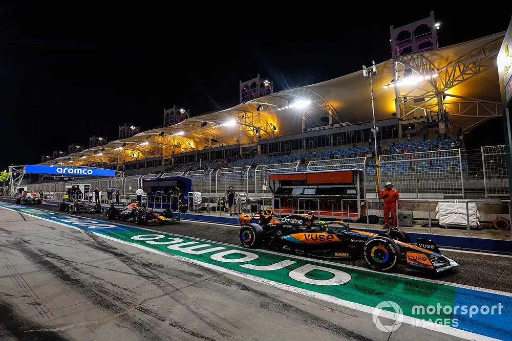 Lando Norris, McLaren MCL60, ahead of Sergio Perez, Red Bull Racing RB19 in the pit lane