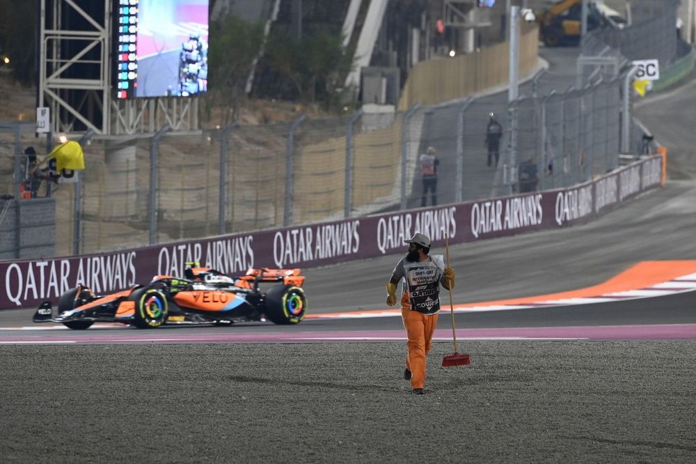 Lando Norris, McLaren MCL60, pasa mientras un comisario limpia una trampa de grava.