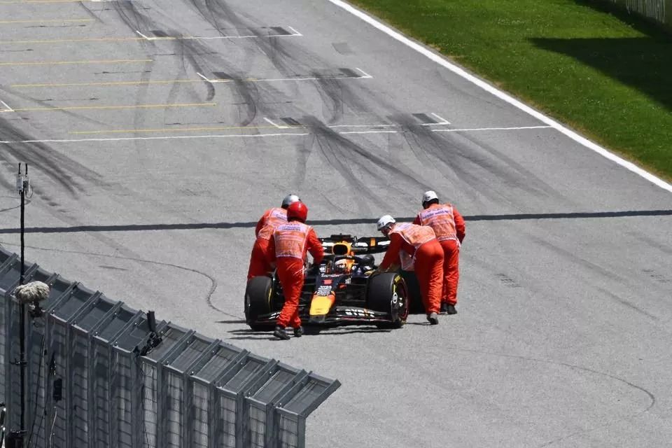 Marshals push the car of Max Verstappen, Red Bull Racing RB20, back to his garage