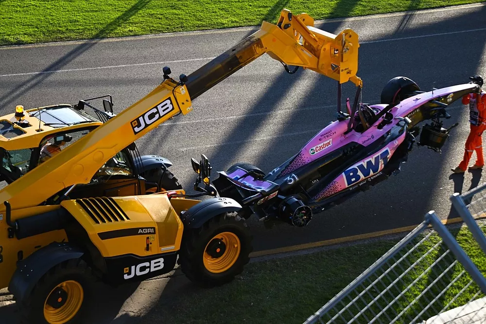 Marshals remove the damaged car of Esteban Ocon, Alpine A523, from the circuit with a JCB