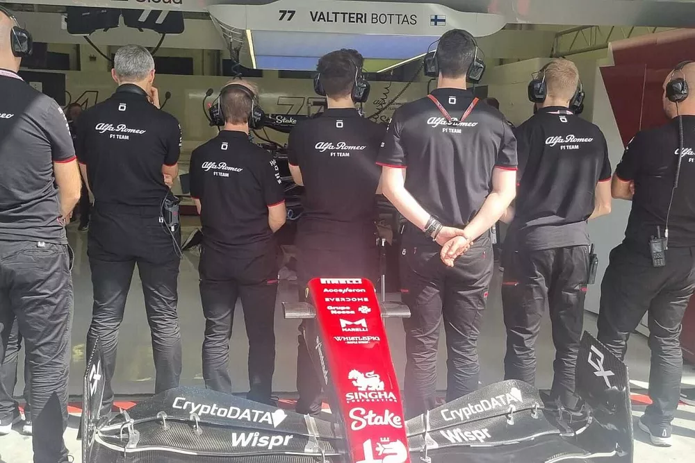 Miembros del equipo Alfa Romeo tapan el coche averiado