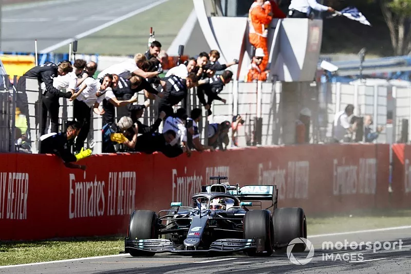 
Il vincitore della gara guida oltre il traguardo sventolando la bandiera a scacchi con la Mercedes AMG F! Team festeggia
