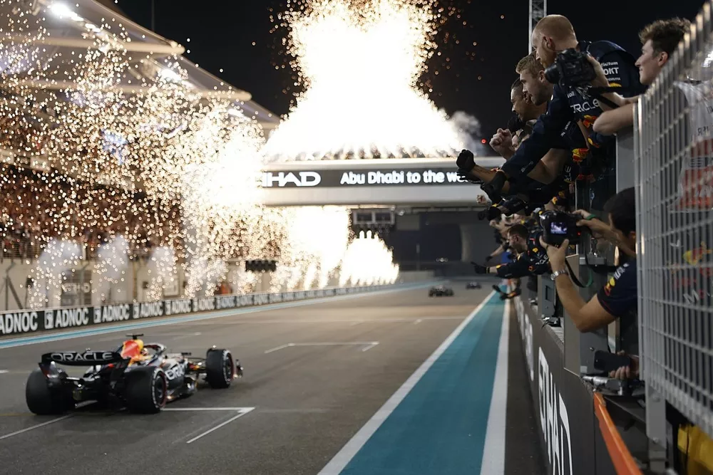 Fireworks light the sky as the Red Bull Racing team cheer Max Verstappen, Red Bull Racing RB19, 1st position, over the line from the pit wall