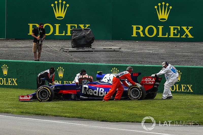 El coche de Carlos Sainz Jr., Scuderia Toro Rosso STR12 es quitado por los oficiales después de aban