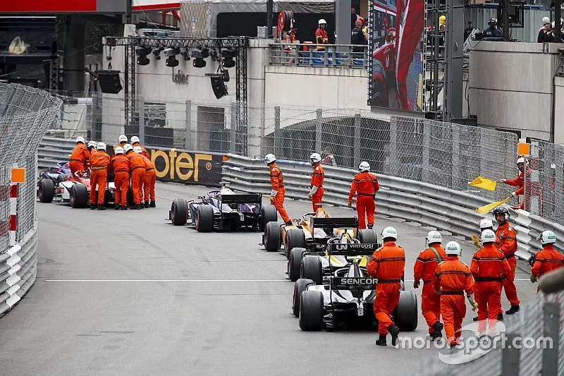Marshals go to push cars lining up after the race is red flagged