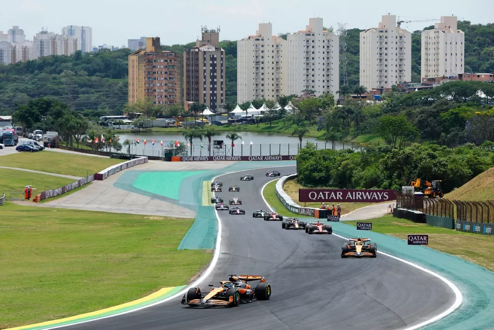 Oscar Piastri, McLaren MCL38 Lando Norris, McLaren MCL38, Charles Leclerc, Ferrari SF-24, Max Verstappen, Red Bull Racing RB20, an the rest of the field on the opening lap
