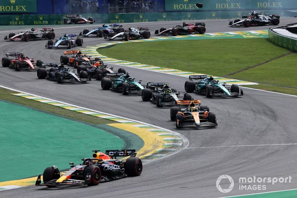Max Verstappen, Red Bull Racing RB19, Lando Norris, McLaren MCL60 and the rest of the field as Kevin Magnussen, Haas VF-23, Alex Albon, Williams FW45, crash