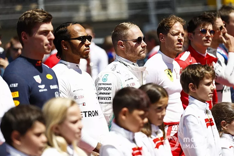 Max Verstappen, Red Bull Racing, Lewis Hamilton, Mercedes AMG F1, Valtteri Bottas, Mercedes AMG F1, Sebastian Vettel, Ferrari, and Charles Leclerc, Ferrari, line up with the grid kids for the national anthem prior to the start