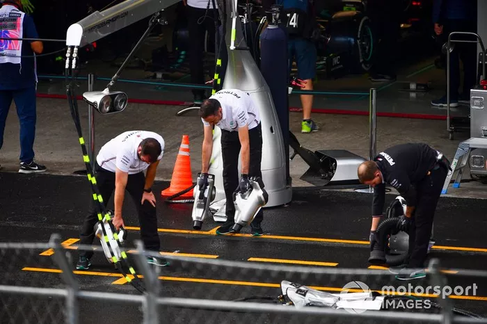 Los mecánicos de Mercedes intentan secar el asfalto fuera de su garaje