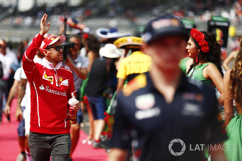 Sebastian Vettel, Ferrari, waves to the crowd, behind Max Verstappen, Red Bull Racing