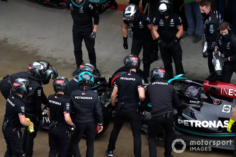 El equipo de boxes de Mercedes inspecciona el alerón delantero dañado del coche de Lewis Hamilton, Mercedes W12