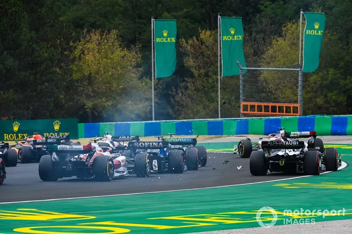 Una colisión hace volar escombros en la primera vuelta mientras Valtteri Bottas, Alfa Romeo C42, Lance Stroll, Aston Martin AMR22, Alex Albon, Williams FW44, Yuki Tsunoda, AlphaTauri AT03, Zhou Guanyu, Alfa Romeo C42, luchan por la posición