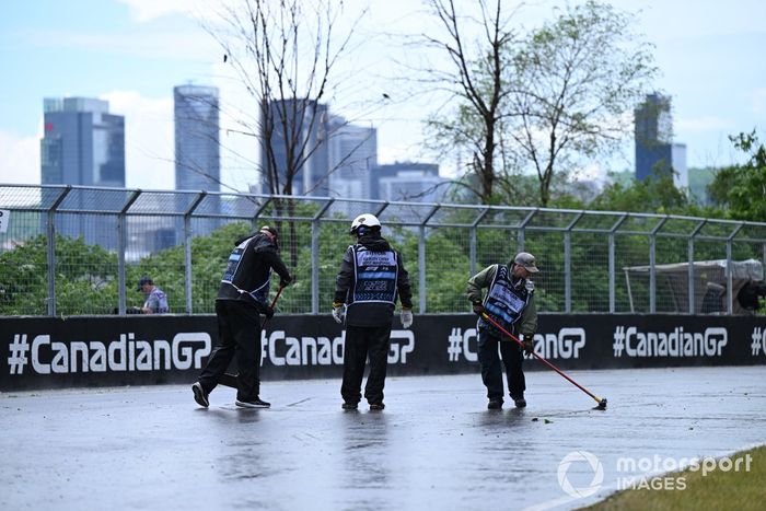 Los comisarios barren el agua de lluvia de la pista
