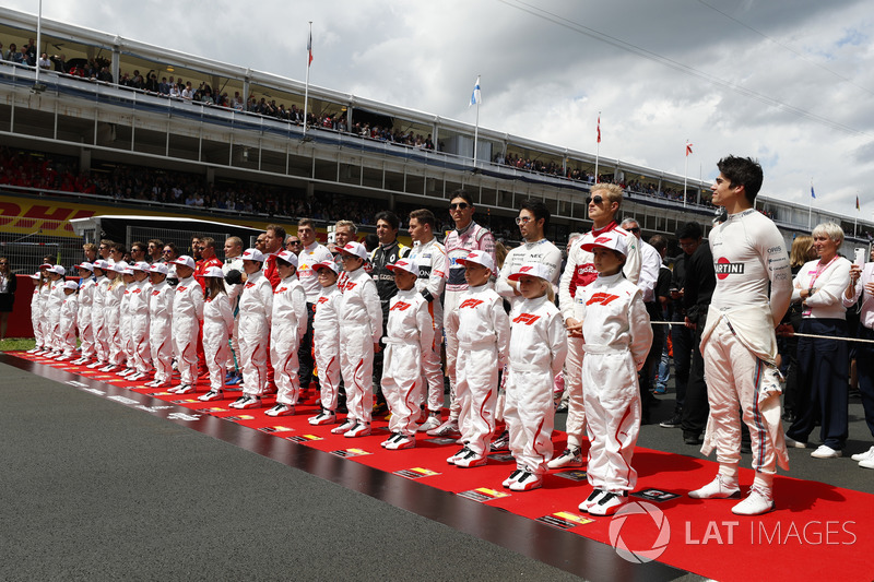 The drivers stand with the grid kids for the national anthem