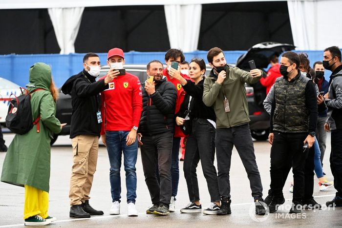 Charles Leclerc, de Ferrari, y Carlos Sainz Jr., de Ferrari, posan con los aficionados para un selfie a su llegada al circuito