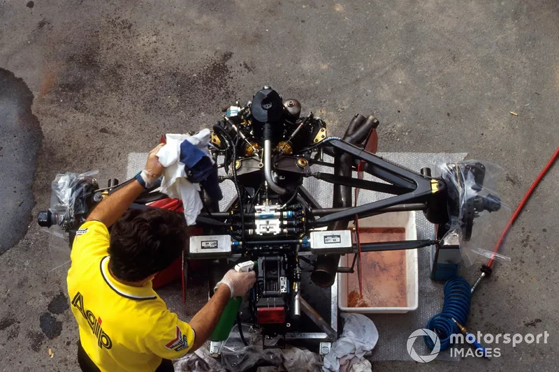 A Ferrari mechanic works on the back end of a stripped down Ferrari F92A