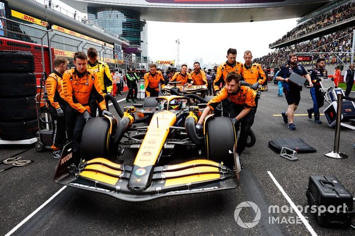 Los mecánicos de McLaren empujan el coche de Oscar Piastri, el McLaren MCL38 hacia su hueco en parrilla
