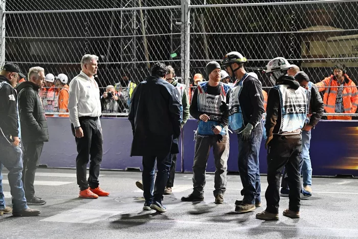 Los comisarios y el personal del circuito se reúnen para reparar una tapa de desagüe en la pista que provocó una bandera roja 