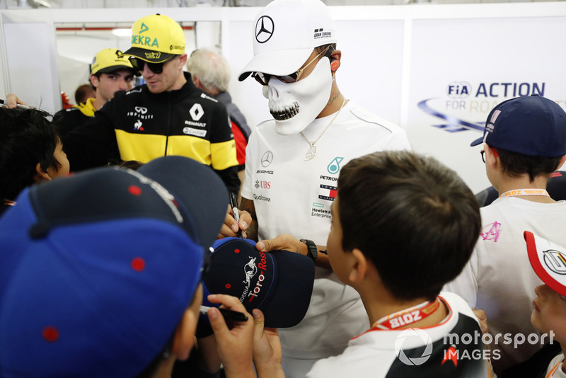 Nico Hulkenberg, Renault Sport F1 Team, and Lewis Hamilton, Mercedes AMG F1, wearing a skull mask, sign autographs for young fans