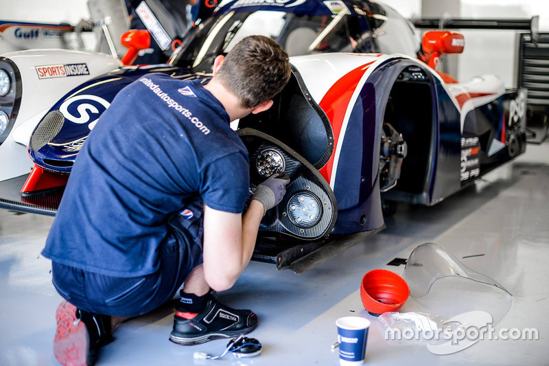 Un membro del team United Autosports applica delle decalcomanie