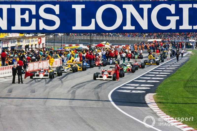 Los monoplazas alineados en la parrilla durante el período de bandera roja. Ayrton Senna de pie junto a su McLaren MP4-5 Honda