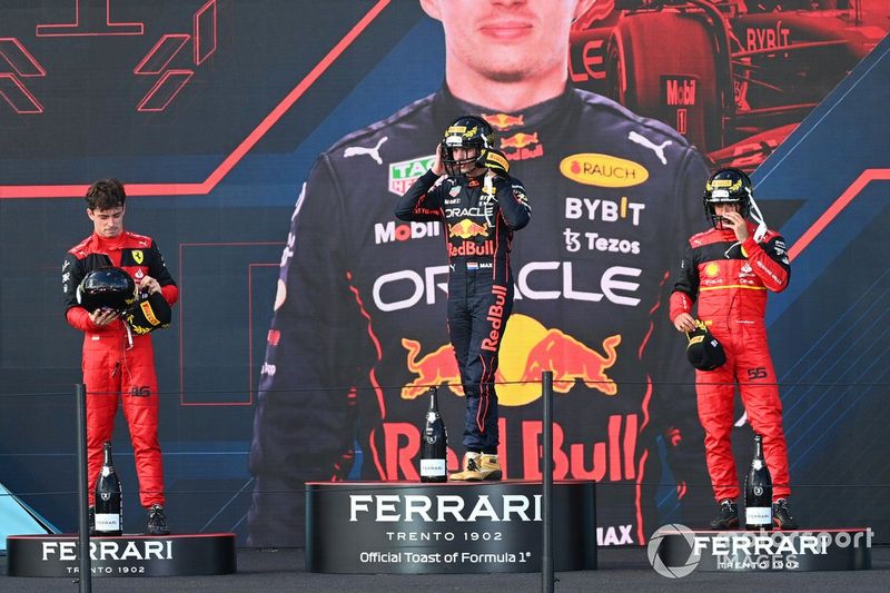 Charles Leclerc, Ferrari, segundo, Max Verstappen, Red Bull Racing, ganador y Carlos Sainz, Ferrari, tercero, en el podio con cascos de fútbol americano