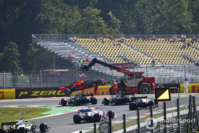 Oficiales de pista remueven el monoplaza de Max Verstappen, Red Bull Racing RB16, mientras pasa Lewis Hamilton, Mercedes F1 W11