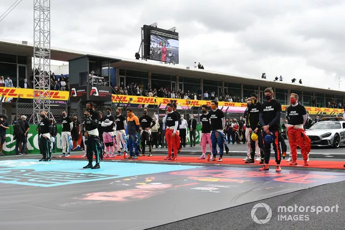 Los pilotos se ponen de pie para el himno nacional antes de la salida en sus camisetas de 