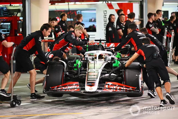L'équipe des stands de Haas F1 Team pousse la voiture de Kevin Magnussen, Haas VF-24, dans le garage.