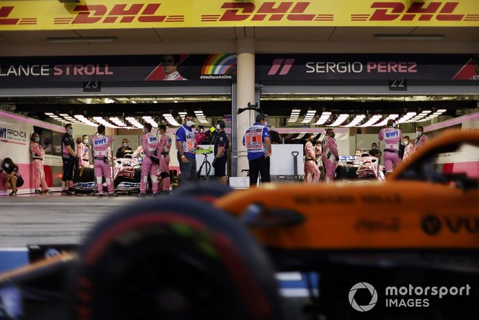 Un McLaren pasa por el garaje de boxes de Racing Point de Lance Stroll, Racing Point RP20 y Sergio Pérez, Racing Point RP20 