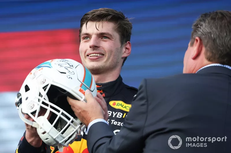 Max Verstappen, Red Bull Racing, 1ª posición, recibe un casco de fútbol de los Miami Dolphins en el podio