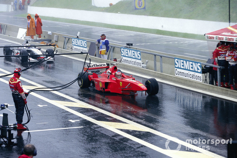 Michael Schumacher, Ferrari F300, con la rueda delantera y el ala faltantes, y David Coulthard, McLaren MP4-13 Mercedes, sin el alerón trasero, en el pitlane