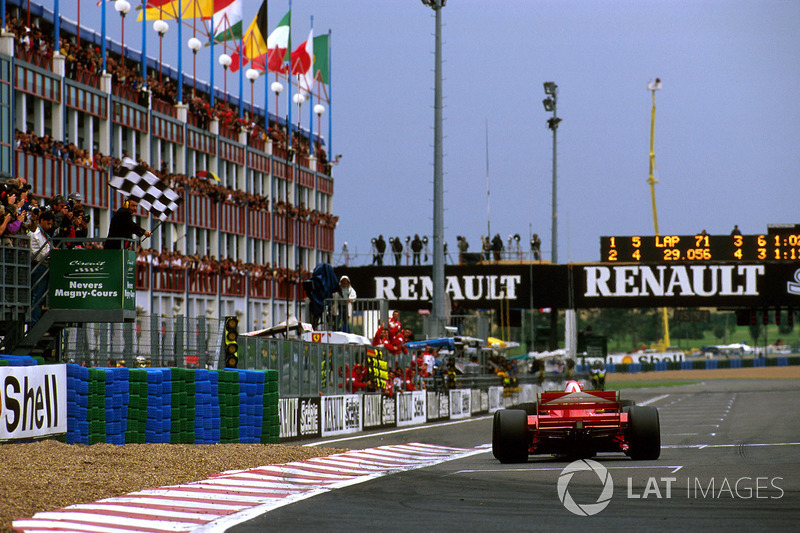 Michael Schumacher, Ferrari F310B, takes the chequered flag