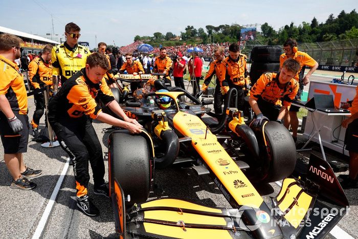Los mecánicos de McLaren empujan el coche de Lando Norris, el McLaren MCL38 hacia su hueco en parrilla