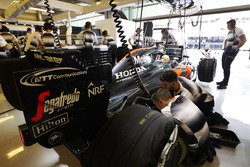 The team work on the car of Fernando Alonso, McLaren in the garage.