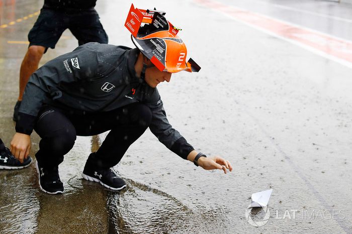 Stoffel Vandoorne, McLaren, pone un barco de papel en la corriente de agua en el pit lane