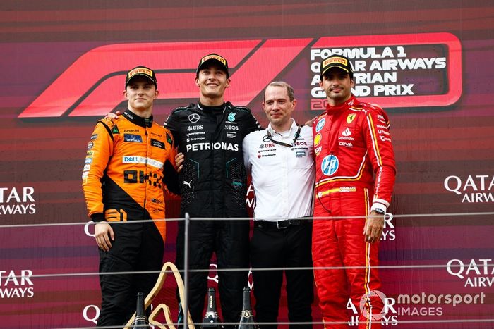 Oscar Piastri, McLaren F1 Team, 2ª posición, George Russell, Mercedes-AMG F1 Team, 1ª posición, el delegado de Mercedes en el trofeo y Carlos Sainz, Scuderia Ferrari, 3ª posición, en el podio.