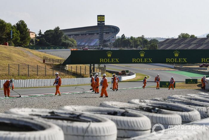Los oficiales de pista barren la grava