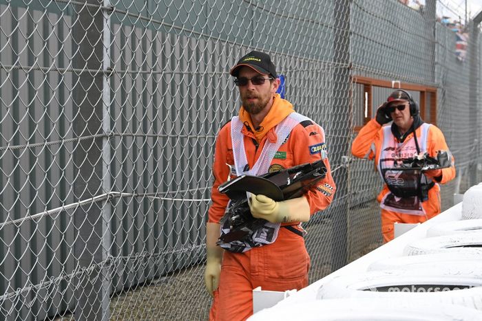 Un comisario recoge los restos tras el accidente de la primera vuelta