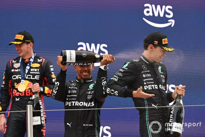 Lewis Hamilton, Mercedes-AMG, 2ª posición, rocía a George Russell, Mercedes-AMG, 3ª posición, con champán en el podio
