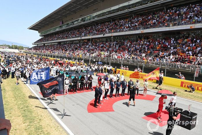 La dirección de la F1, los dignatarios, los invitados y los pilotos se sitúan en la parrilla para escuchar el himno nacional antes de la salida 