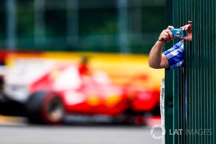 Un fan toma una foto y al fondo pasa Sebastian Vettel, Ferrari SF70H