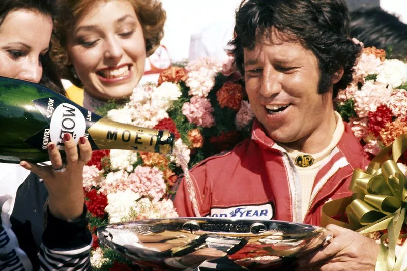 Race winner Mario Andretti, Lotus celebrates on the podium by having his trophy filled with champagne