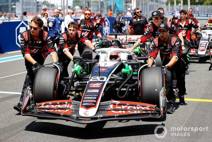 Los mecánicos de Haas F1 Team empujan el coche de Kevin Magnussen, Haas VF-24, hasta su puesto en parrilla